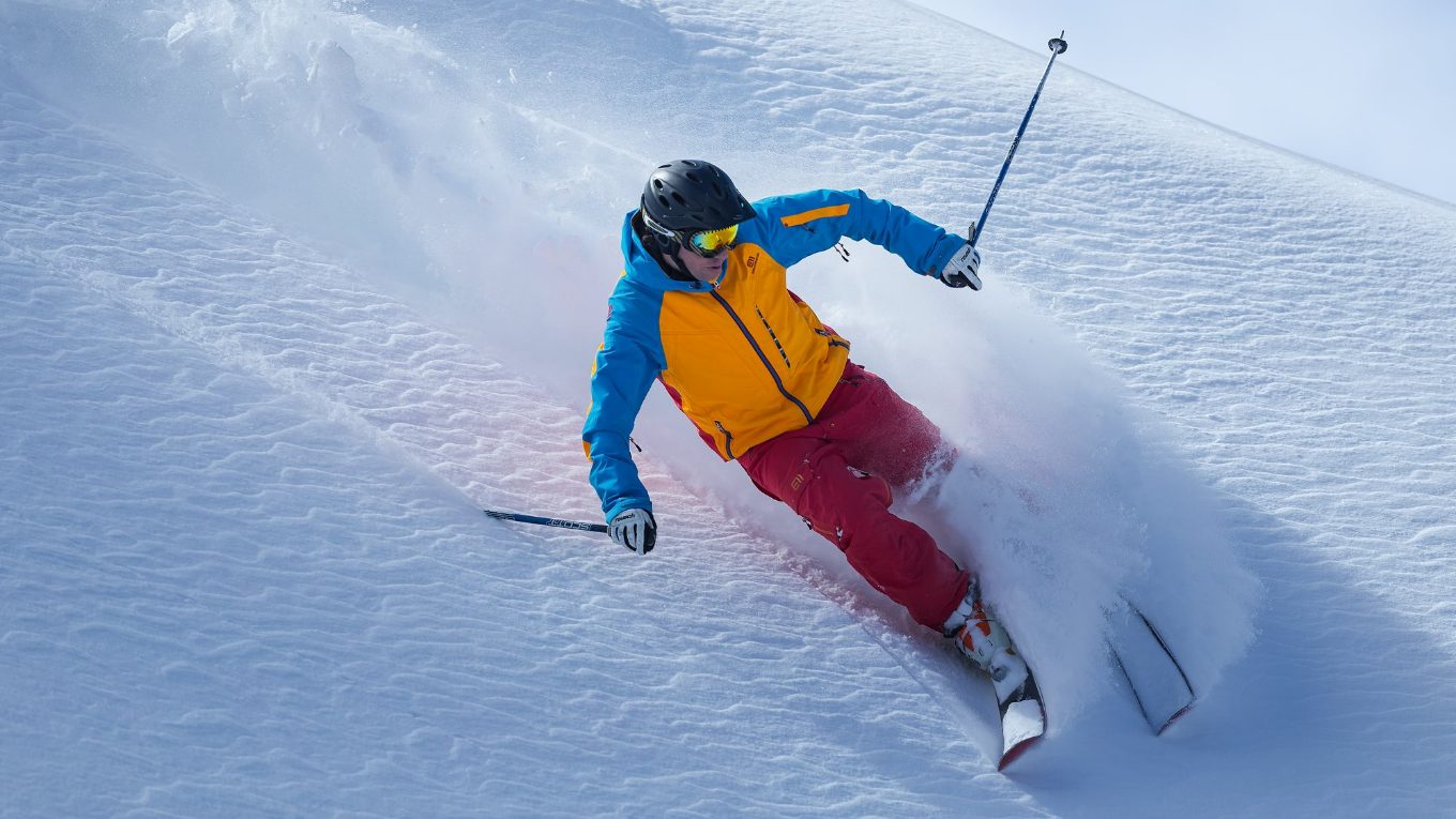 A skier carving a deep turn through fresh powder